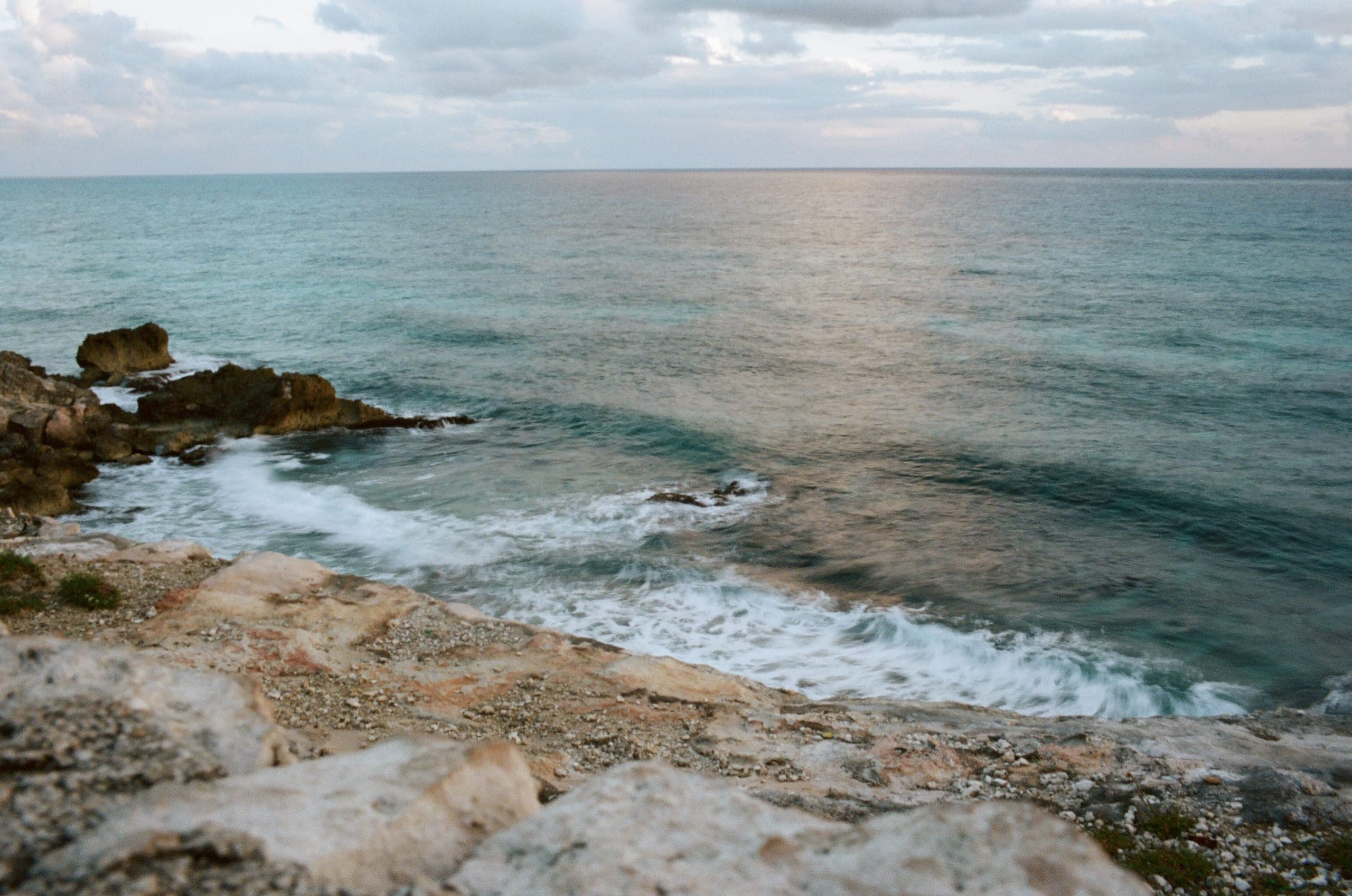Rocky coastline with sea, waves crashing against limestone, overcast sky