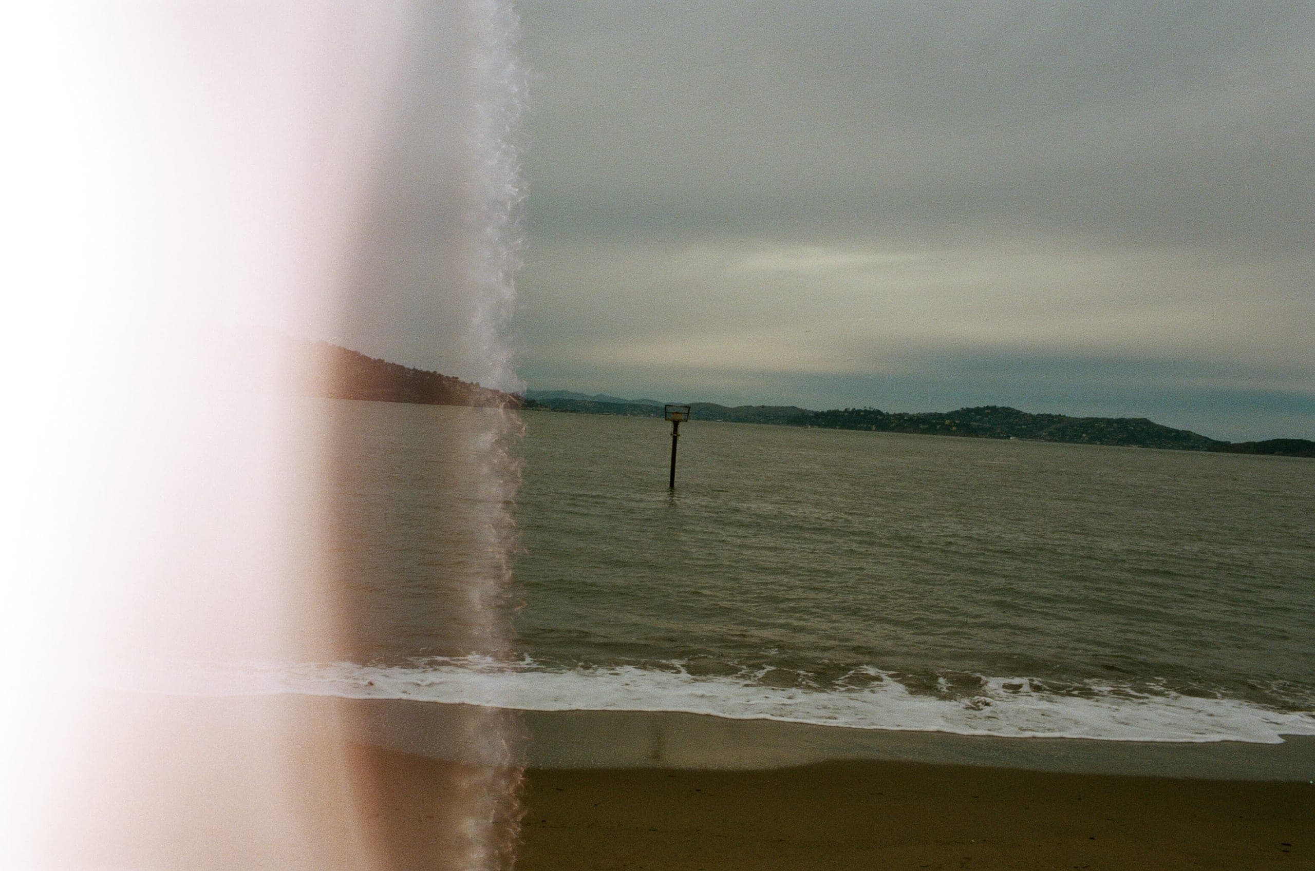 Marin headlands viewed from a San Francisco beach with a pink light leak on the left