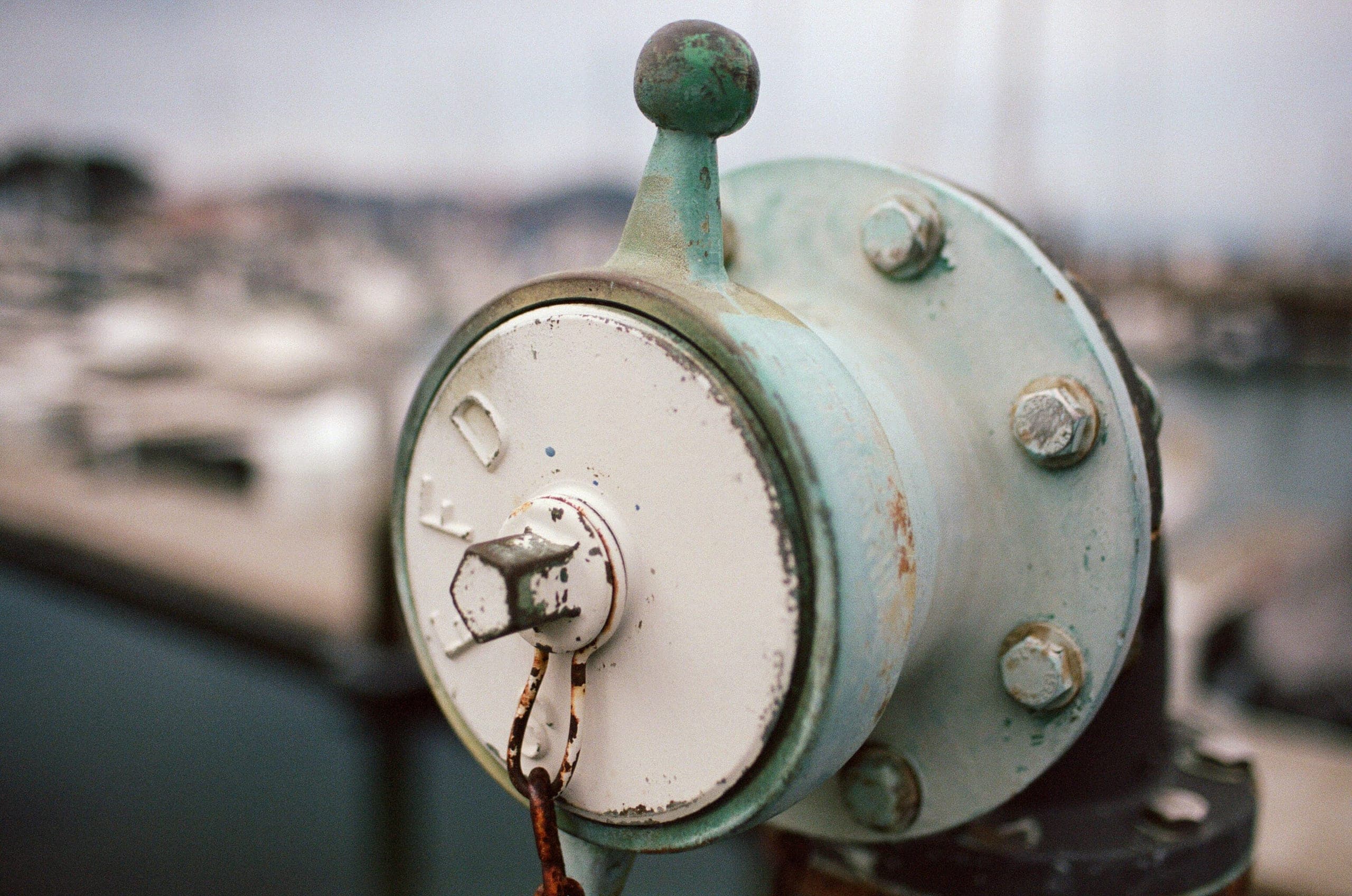 Close-up of an oxidized teal metal bell mechanism on a boat