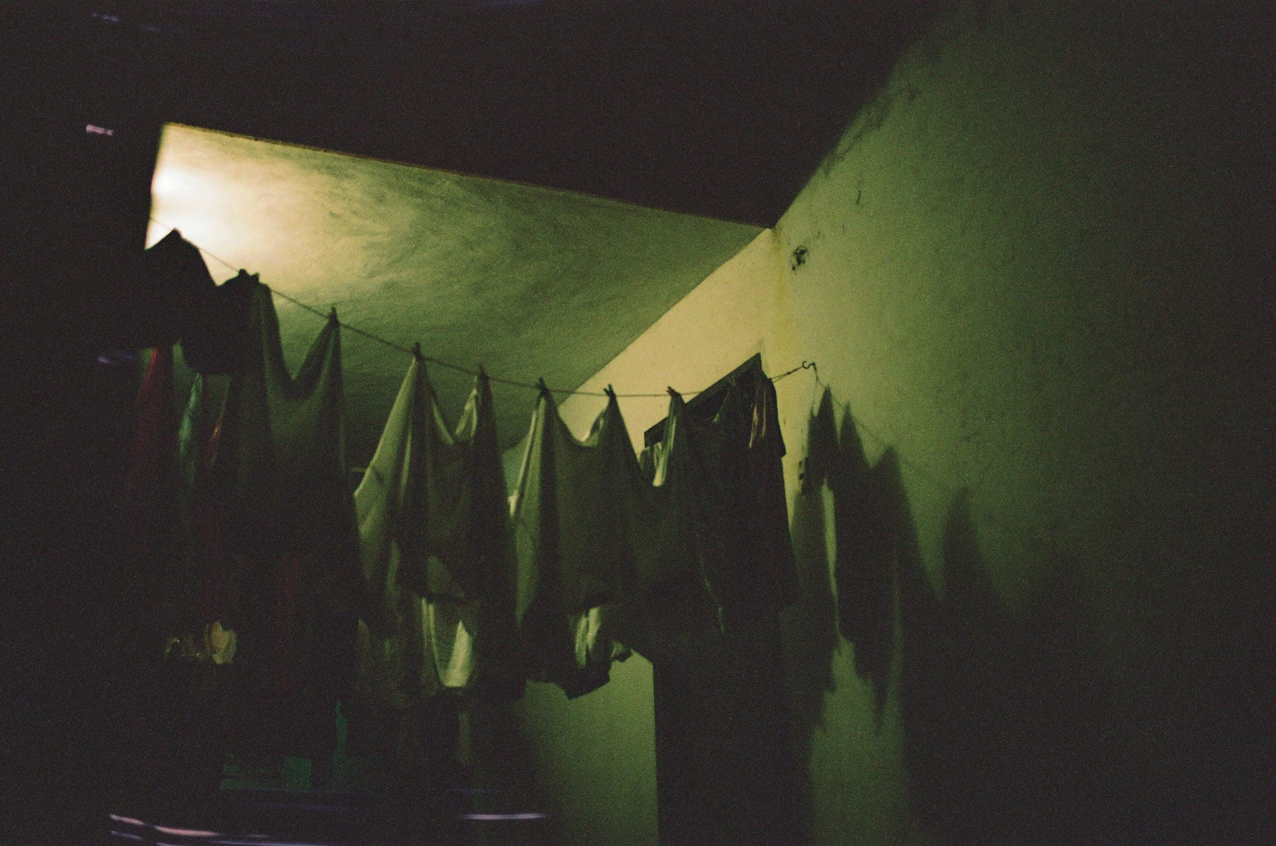 Laundry hanging on a line in a dim green-tinted room