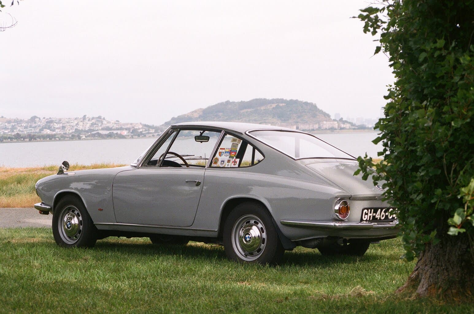 Gray BMW Glas 1700 GT parked on grass looking out at the bay