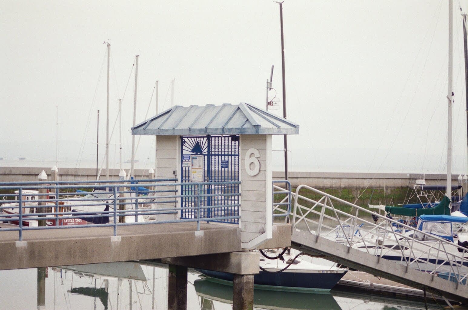 Dock gate marked 6 with sailboats and fog behind